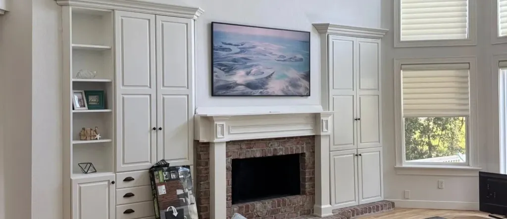 TV mounted above a brick fireplace and flanked by built-in white cabinetry, no visible cables, in a Dallas living room