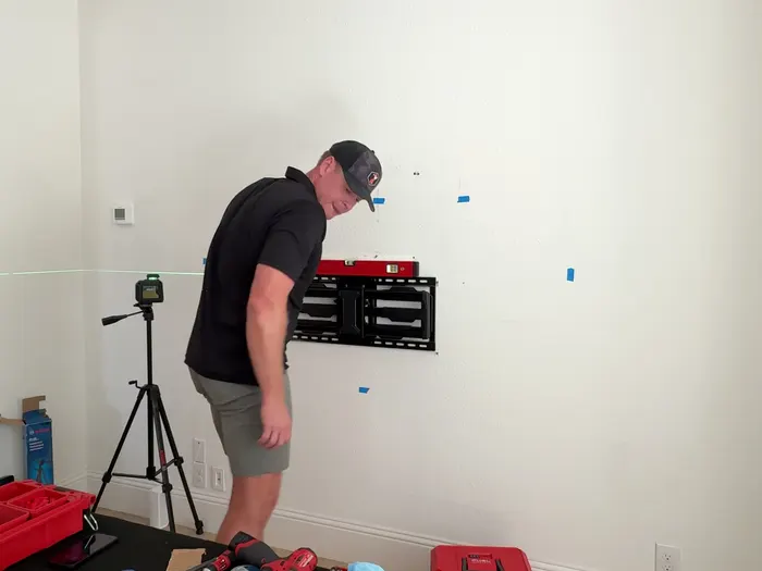 TrueLVL technician checking the level on a wall-mounted TV bracket during an install in Prosper, TX